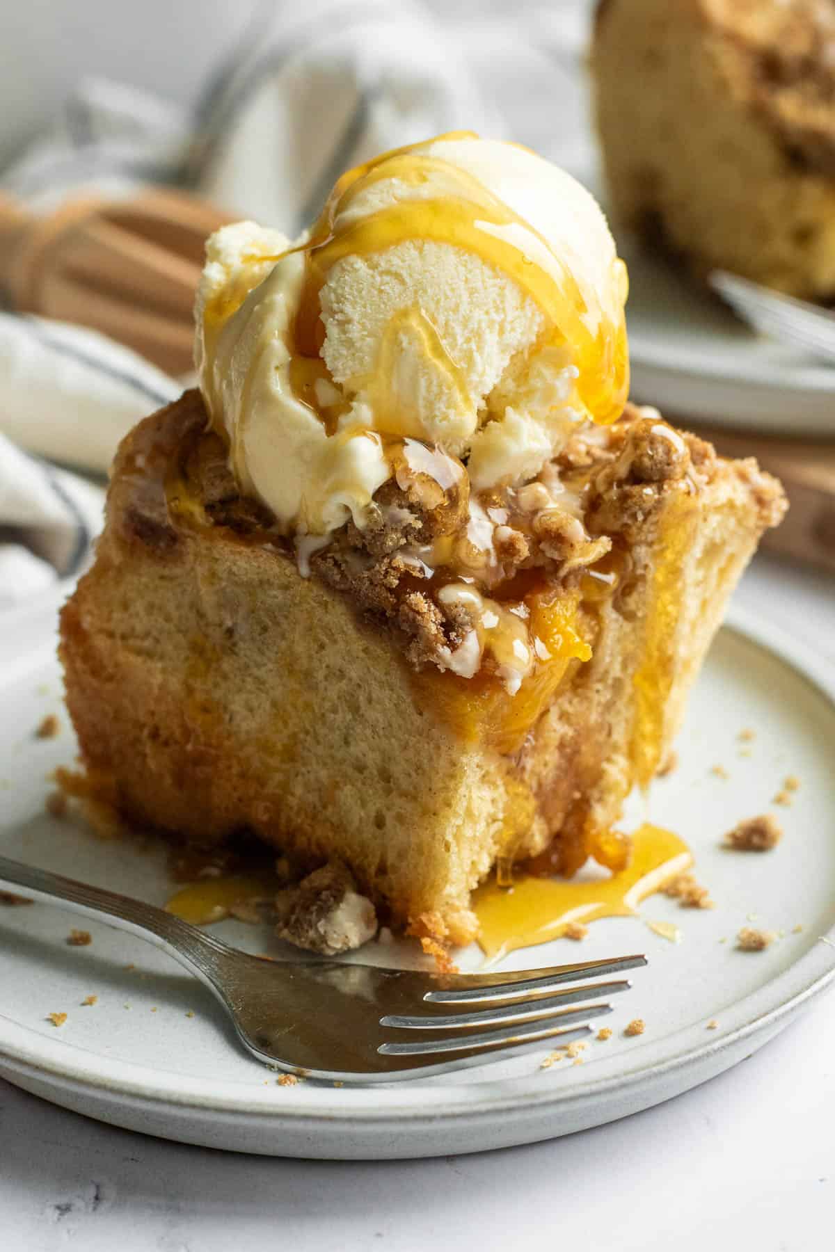 A scoop of vanilla ice cream sitting on top of a cinnamon roll topped with streusel on a grey plate.