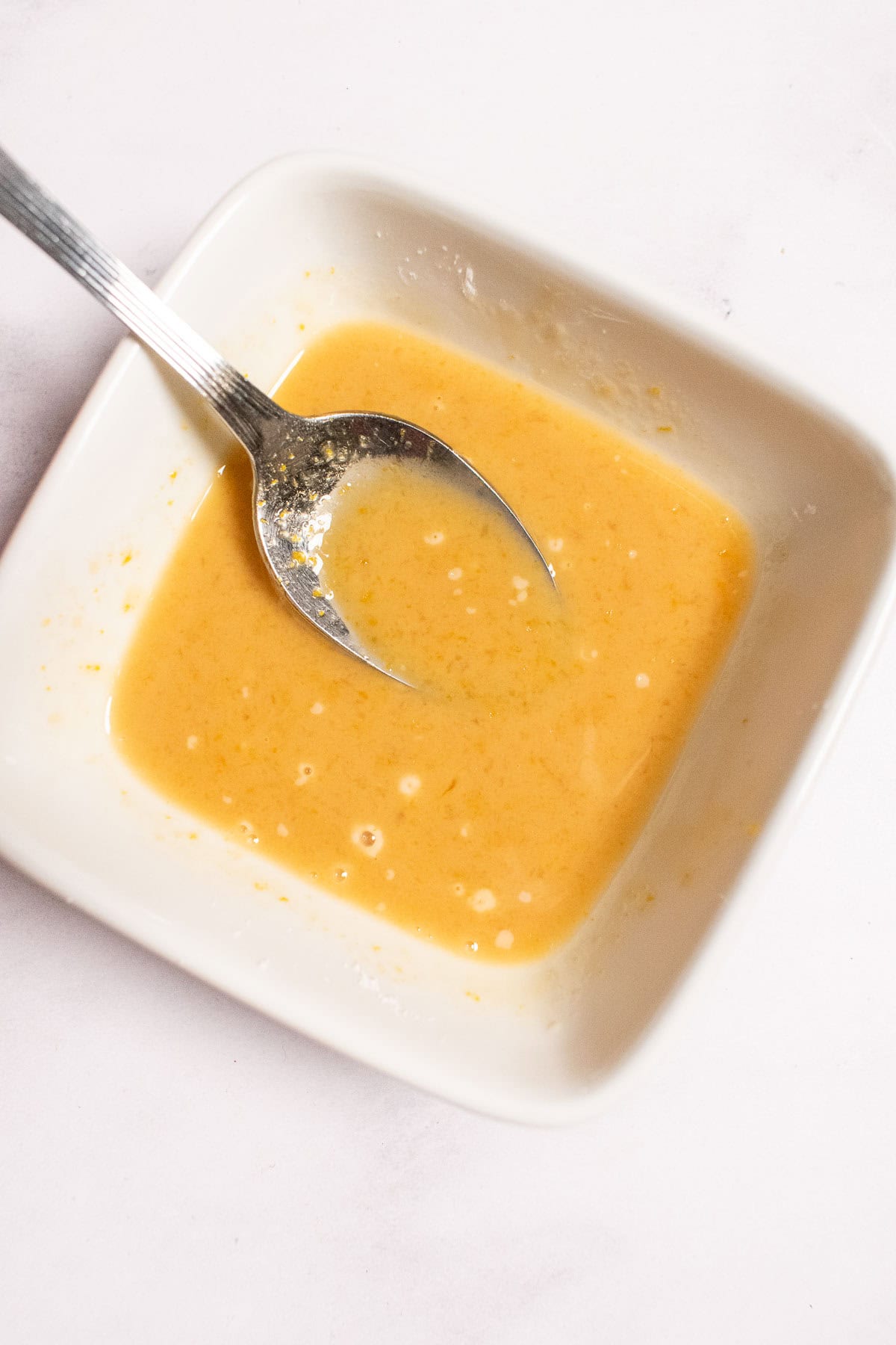 Cornstarch and peach juice mixed in a bowl to form an orange liquid.