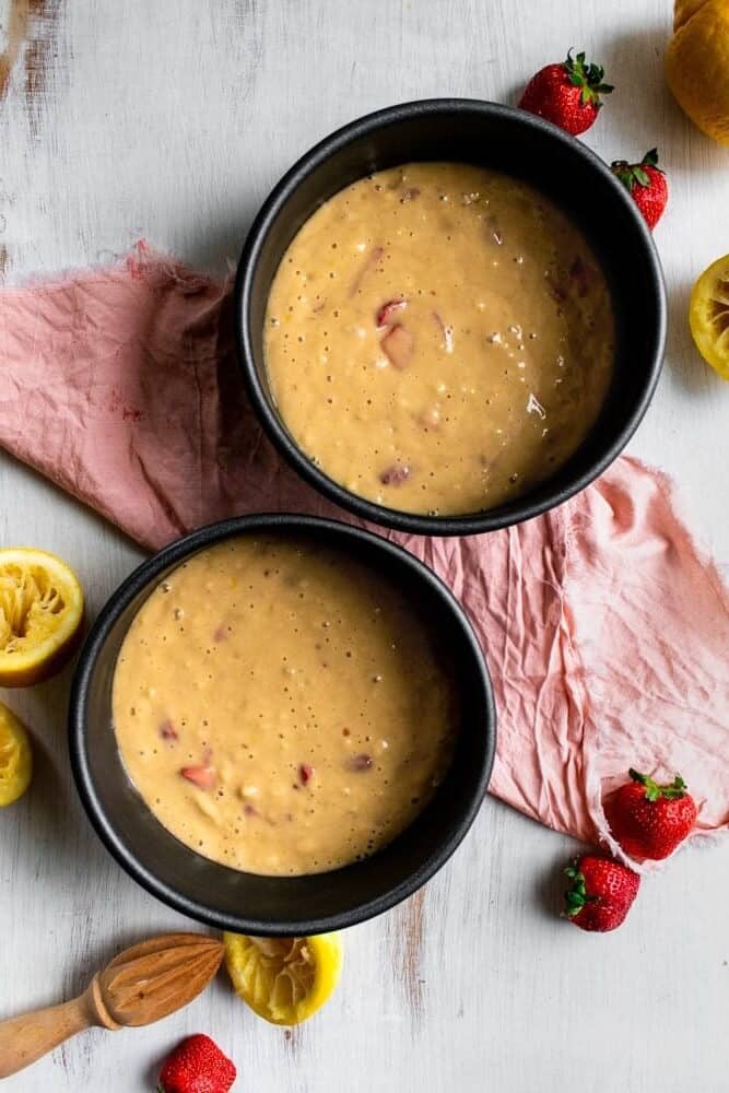 two metal cake tins filled with cake batter.