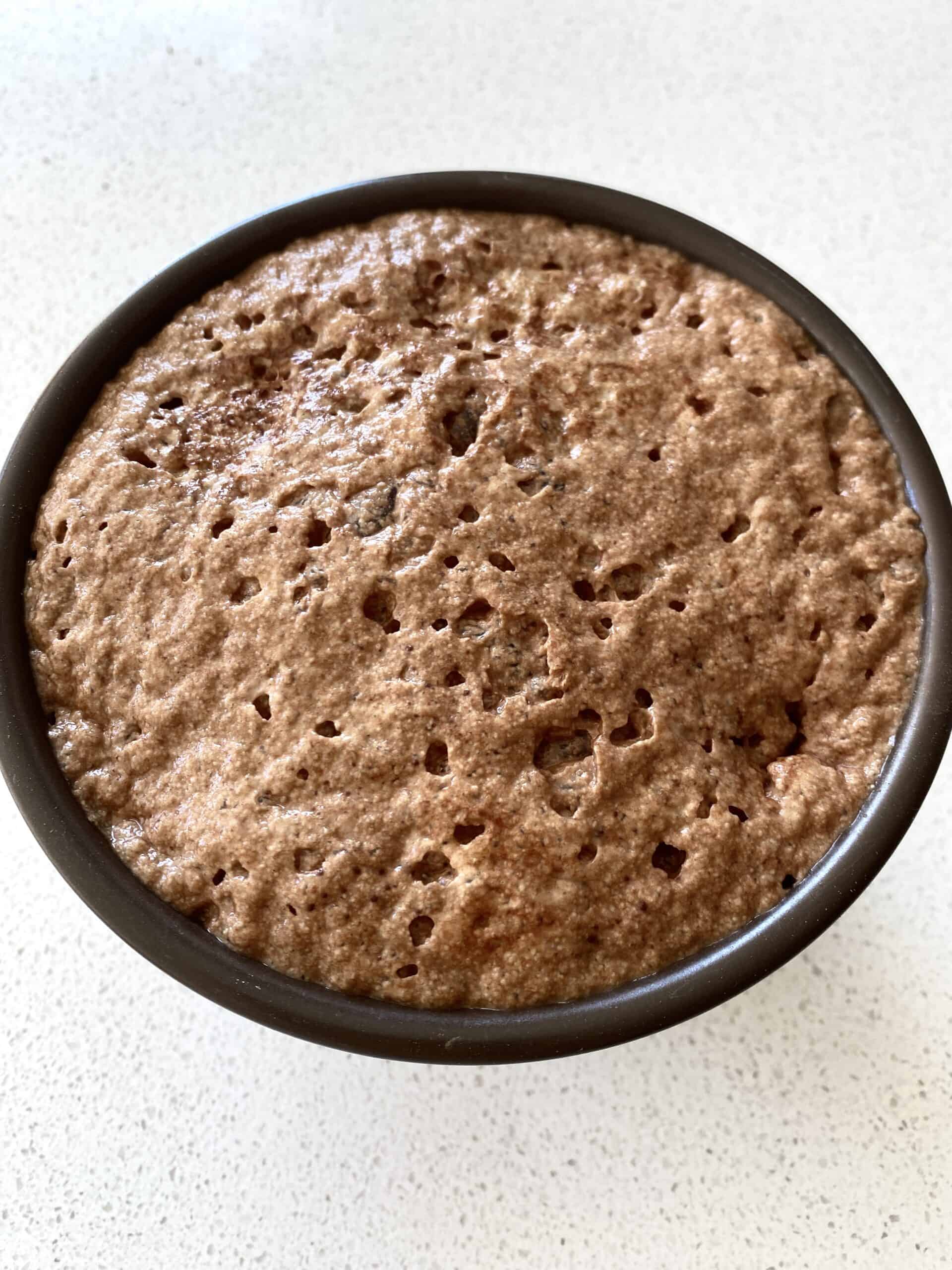 A small brown bowl filled with frothy, activated yeast, water, sugar, and cocoa powder.