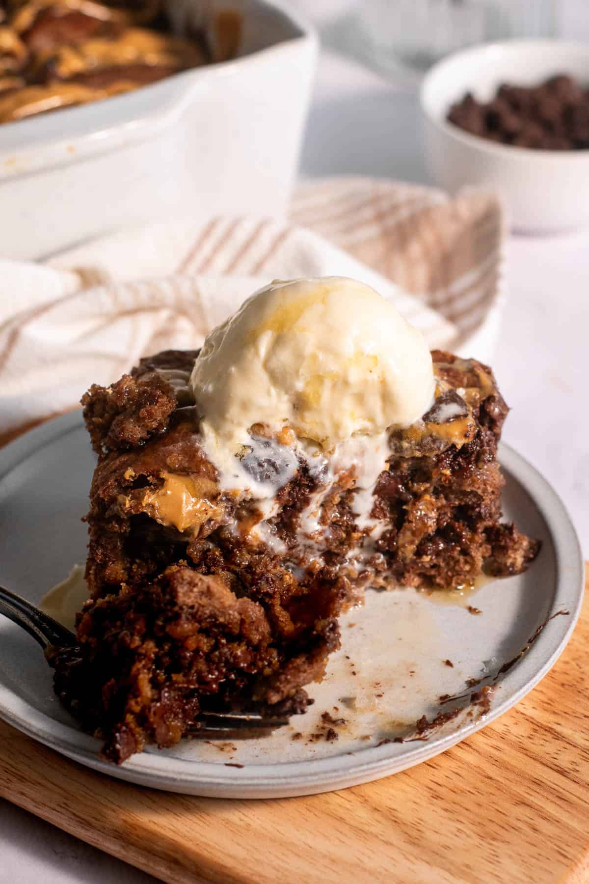 A scoop of vanilla ice cream on top of chocolate peanut butter focaccia on a plate with a large bite taken out of it.