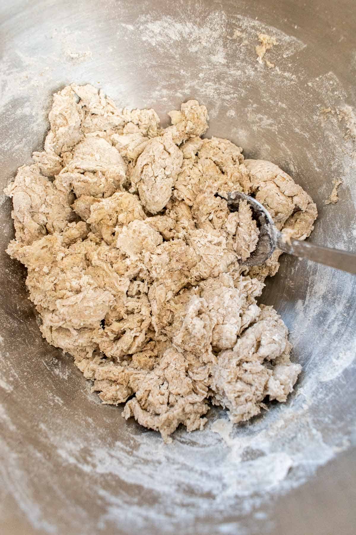 A shaggy, dry dough made with white and rye flour in a metal bowl.