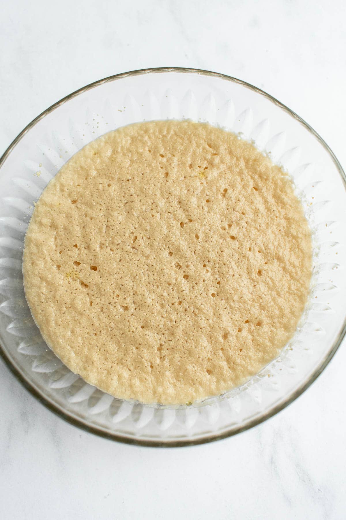 Frothy yeast, water, and sugar in a small glass bowl.