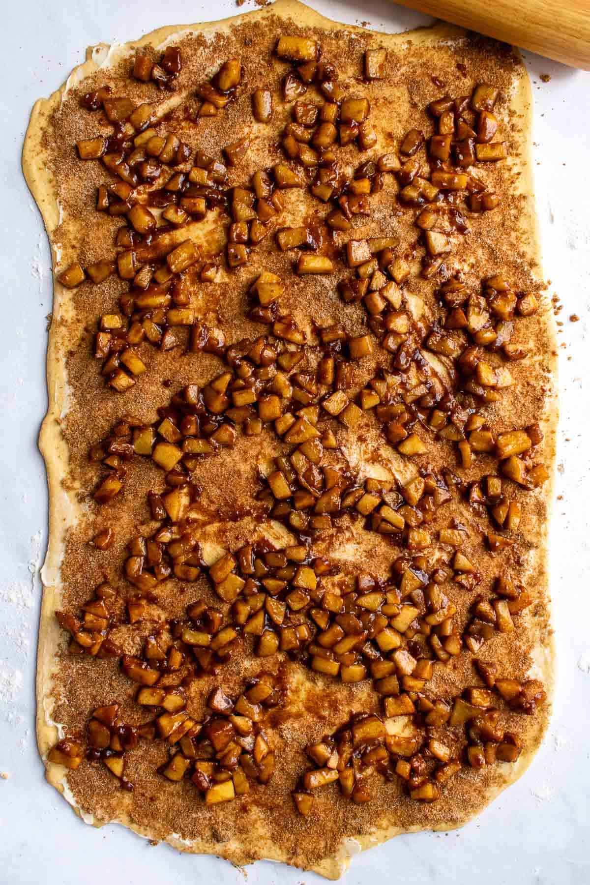A large rectangle of rolled-out dough topped with apple pie filling.