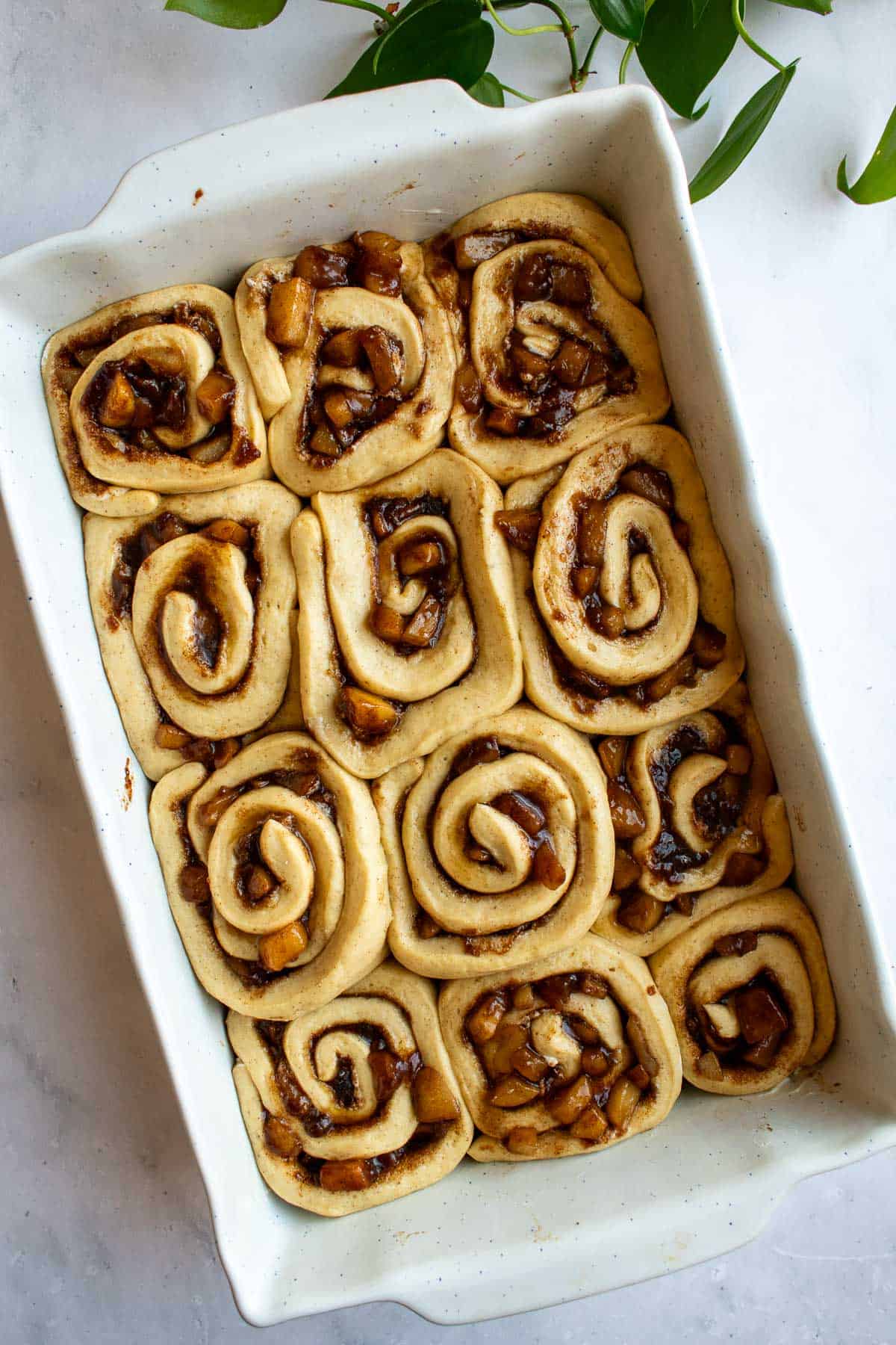 A white baking dish filled with unbaked cinnamon rolls.