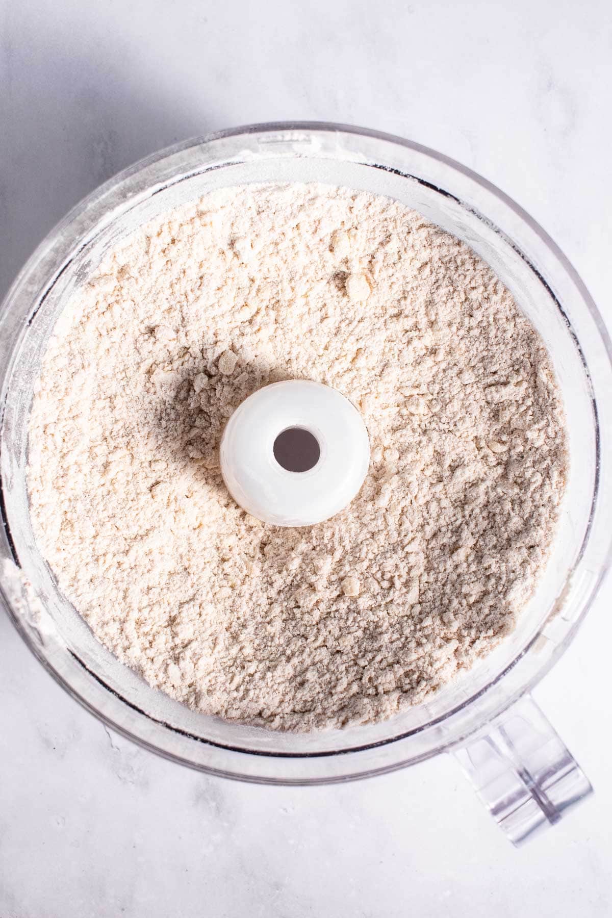 Flour, salt, cinnamon, and butter mixed into a dry, sandy mixture in a food processor.