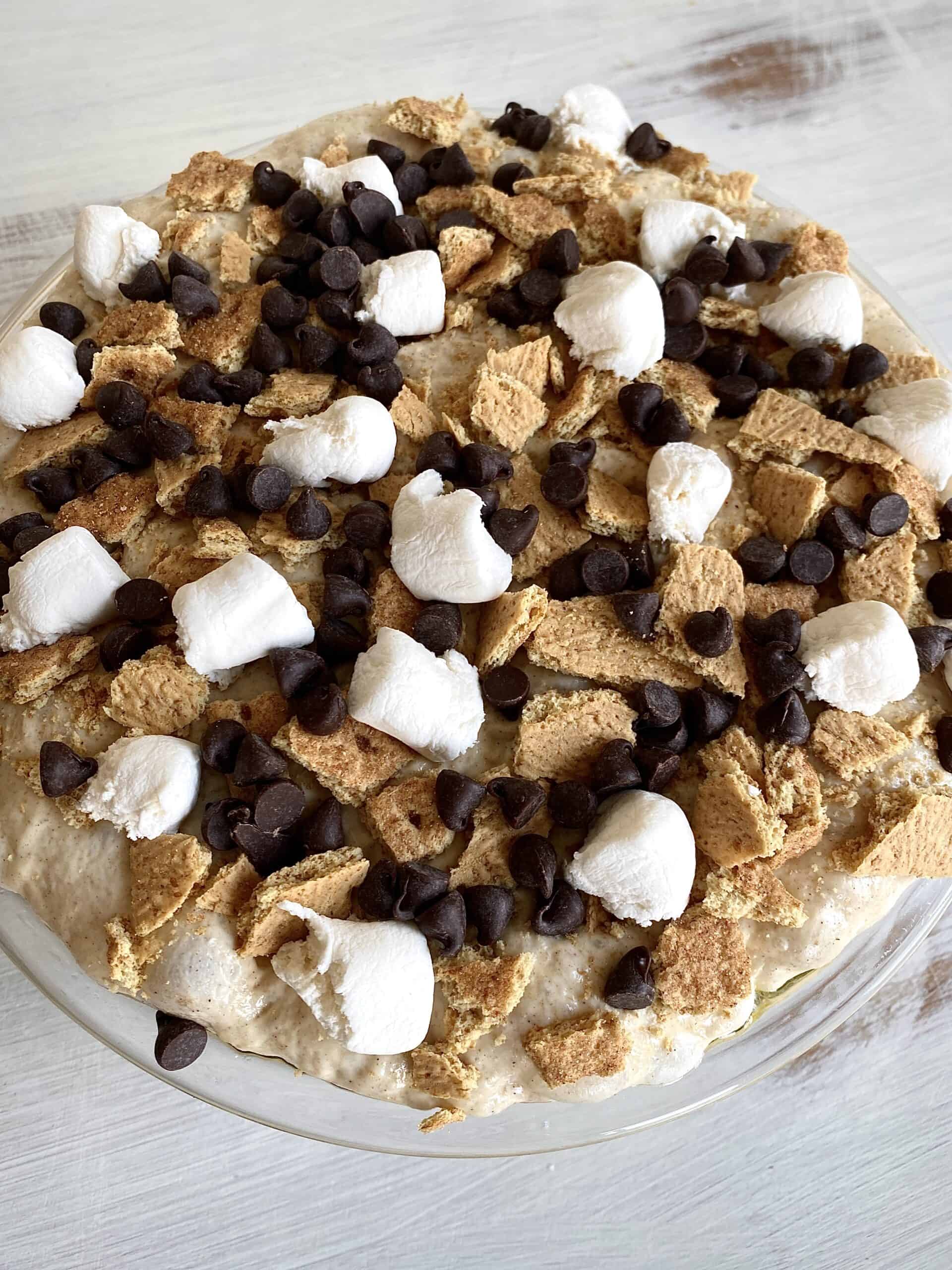 A bowl of bread dough topped with torn marshmallows, crushed graham crackers, and chocolate chips.