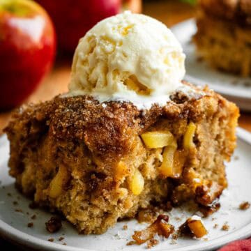 A large square of sweet focaccia with caramelized sugar on top and baked diced apples in the middle, with a scoop of vanilla ice cream on top.