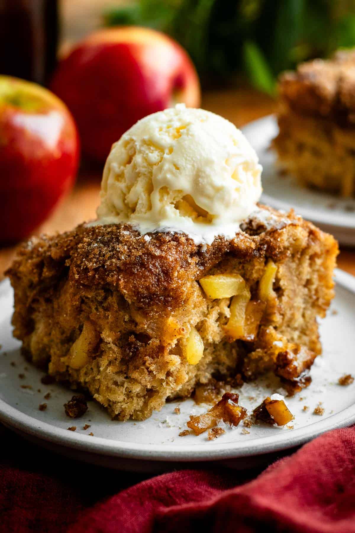 A large square of sweet focaccia with caramelized sugar on top and baked diced apples in the middle, with a scoop of vanilla ice cream on top.