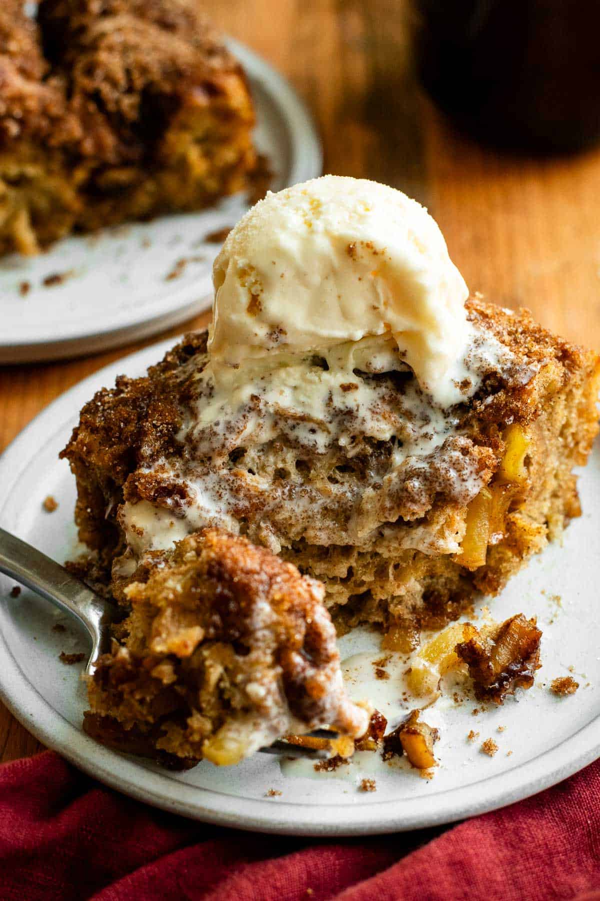 A slice of half-eaten apple focaccia with a melted scoop of vanilla ice cream on top.