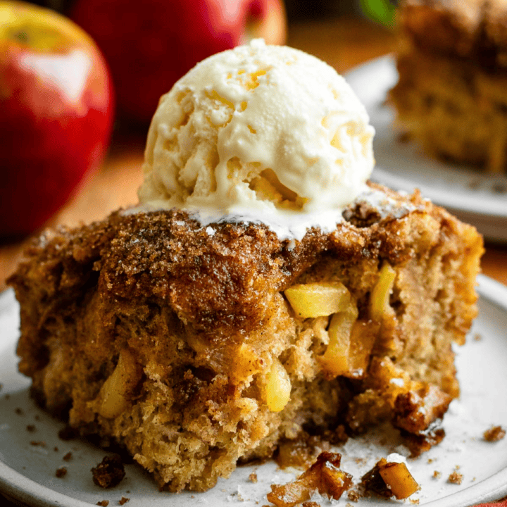 A scoop of vanilla ice cream sitting on top of a large fluffy square of apple donut focaccia bread on a grey plate.