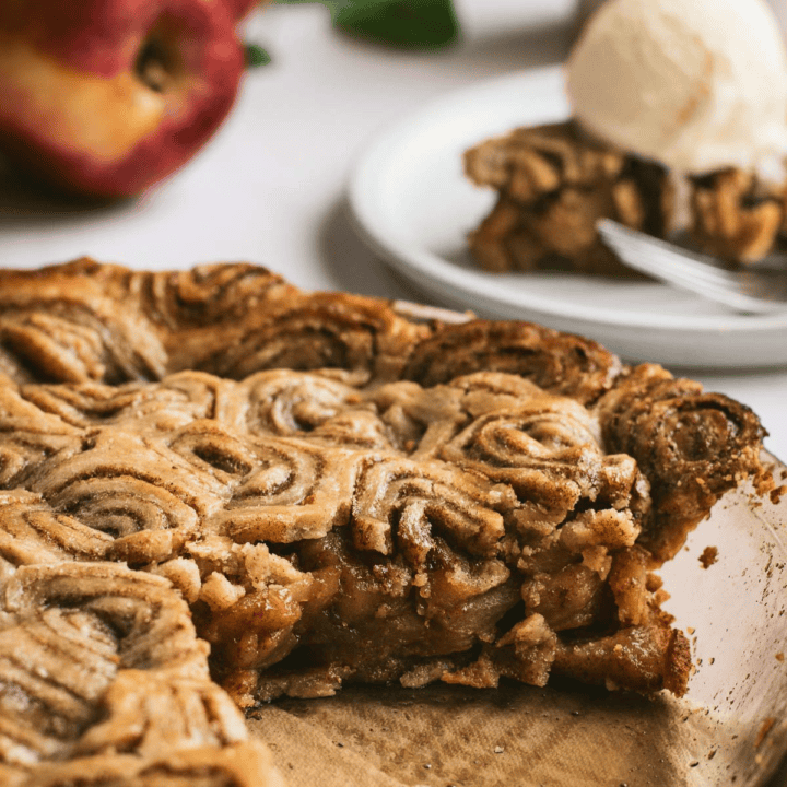 A baked apple pie in a glass dish with a cinnamon roll top crust.