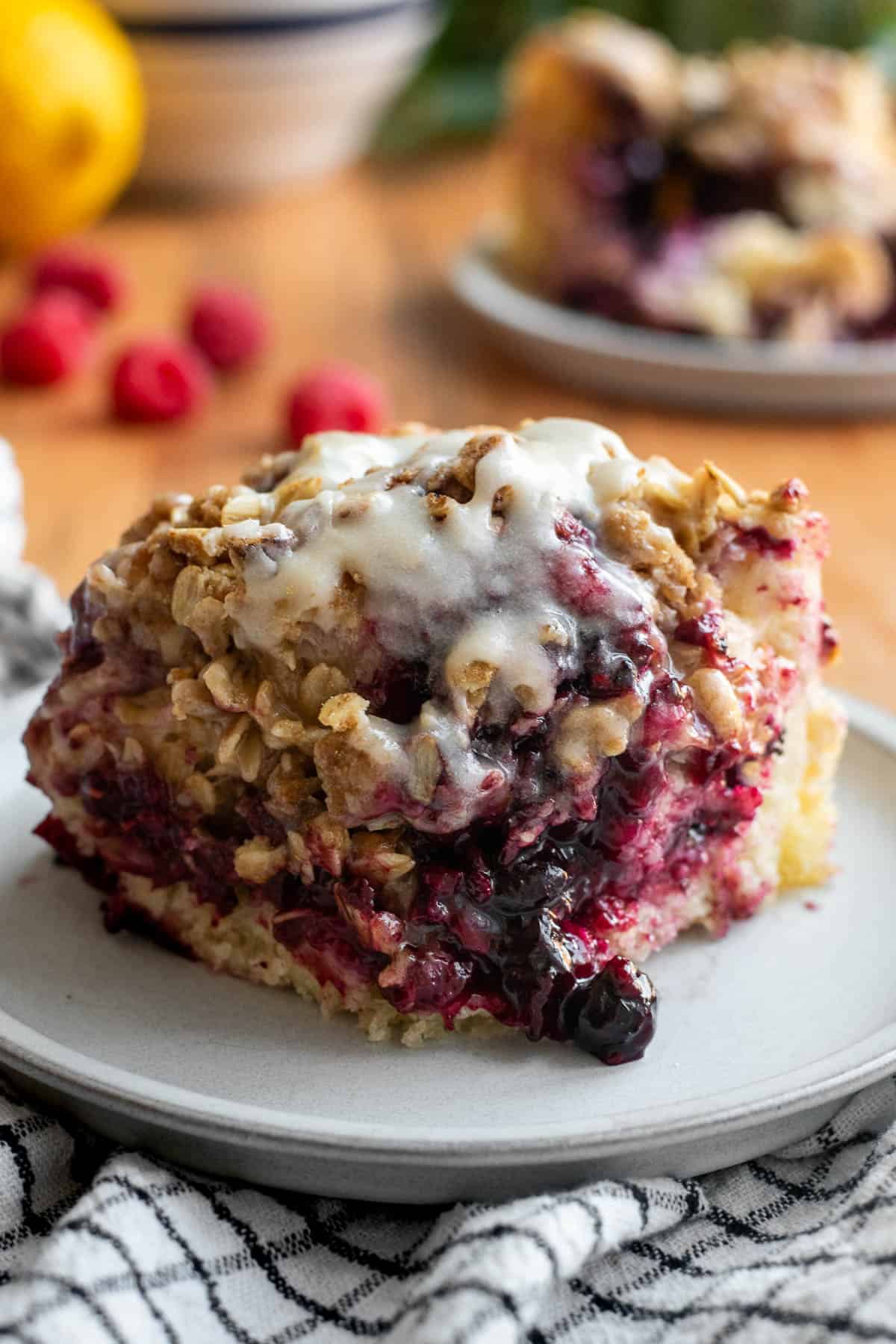 A large square of focaccia filled with berries and topped with glaze and a crumbly oat topping.