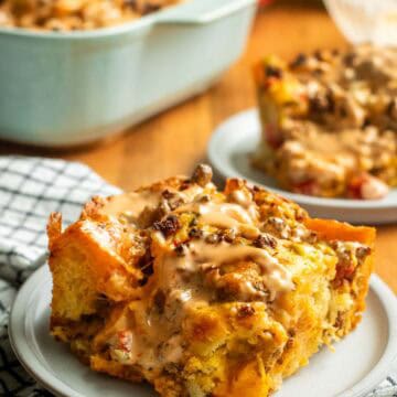 A large square of focaccia on a grey plate topped with ground beef, melted cheese, tomatoes, and light orange sauce.