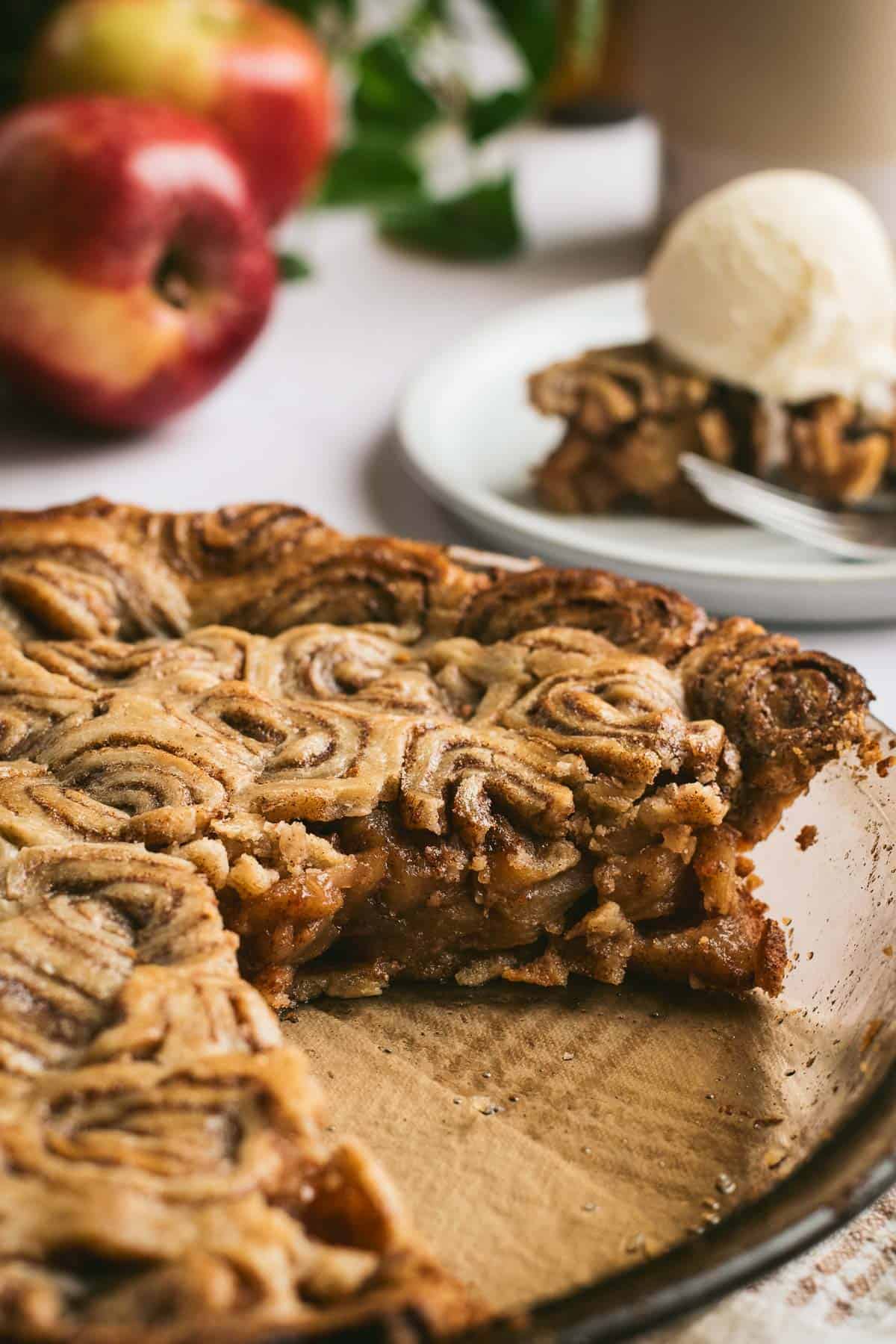 An apple pie in a glass dish topped with a cinnamon roll pie crust.