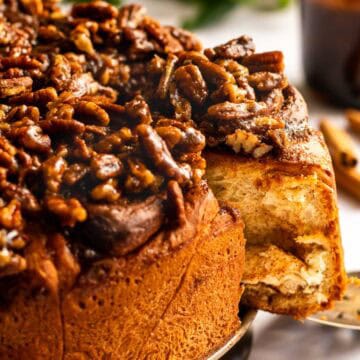Cinnamon rolls on a round pan bottom topped with a brown sugar coating and pecans.