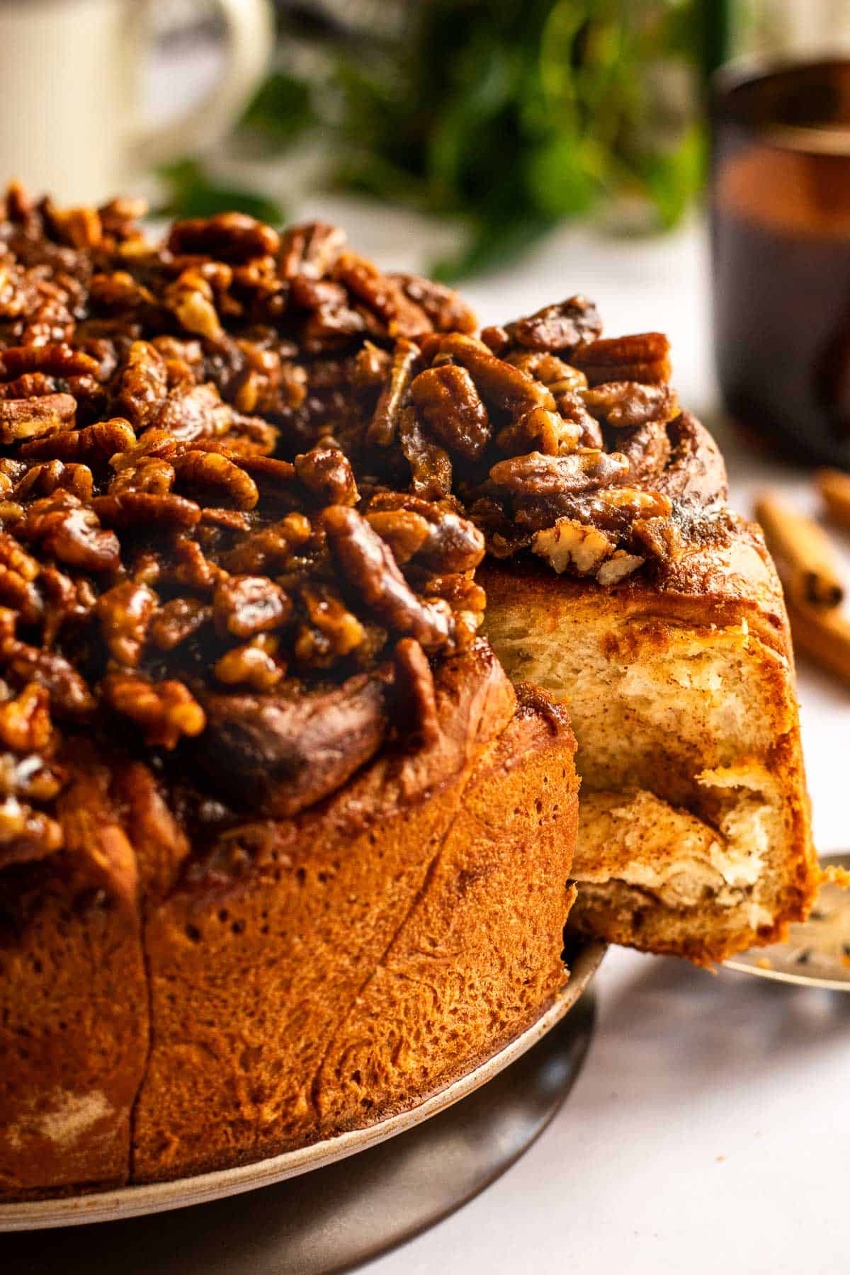 Cinnamon rolls on a round pan bottom topped with a brown sugar coating and pecans.