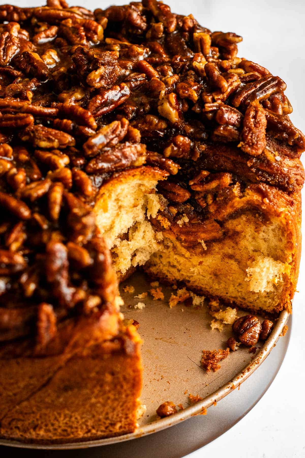 The bottom of a cake pan topped with tall, fluffy pecan cinnamon rolls.
