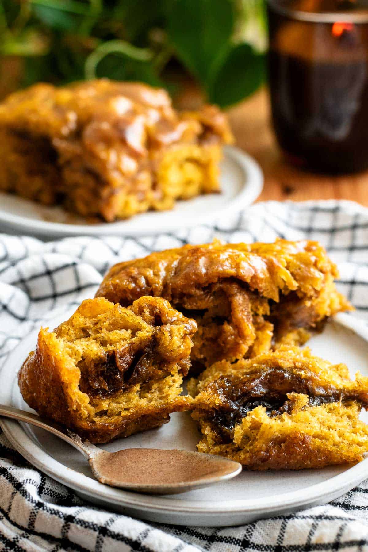 Three separate pieces of orange pumpkin focaccia torn apart to show the gooey brown cinnamon roll filling inside.