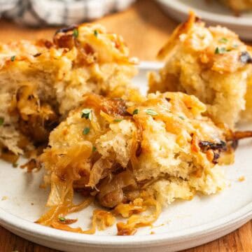 Three small pieces of focaccia topped and filled with caramelized onions on a grey plate.