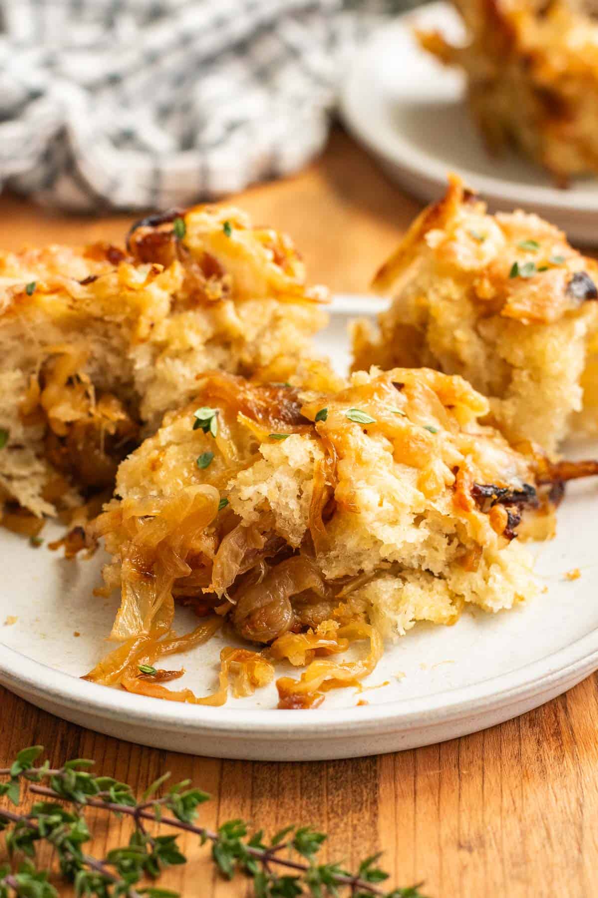 Three small pieces of focaccia topped and filled with caramelized onions on a grey plate. 