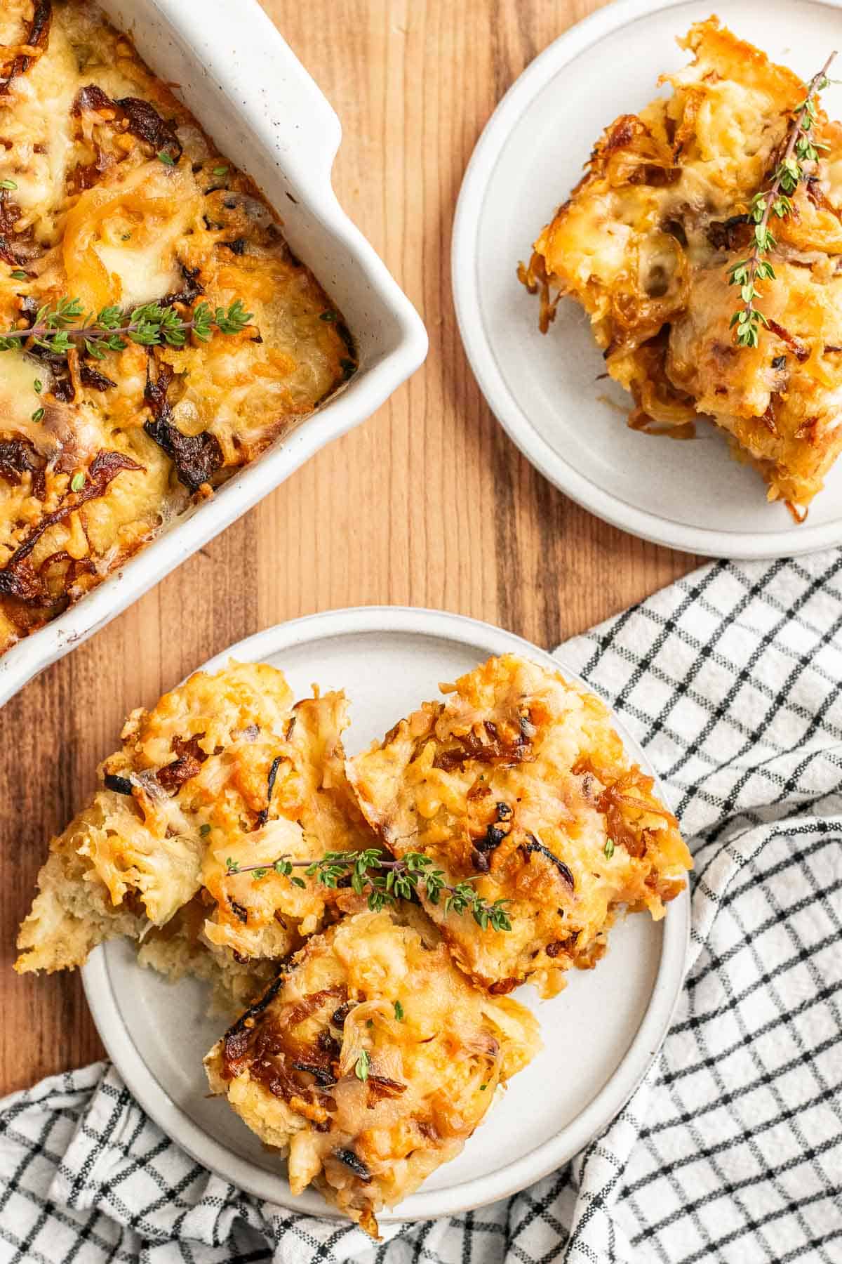 Two plates filled with slices of caramelized onion focaccia on a table next to a baking dish with more focaccia inside.