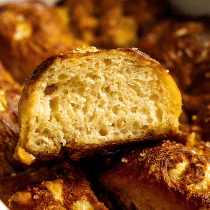 A slice of pretzel focaccia cut open to show the airy crumb sitting on top of more baked pretzel focaccia.