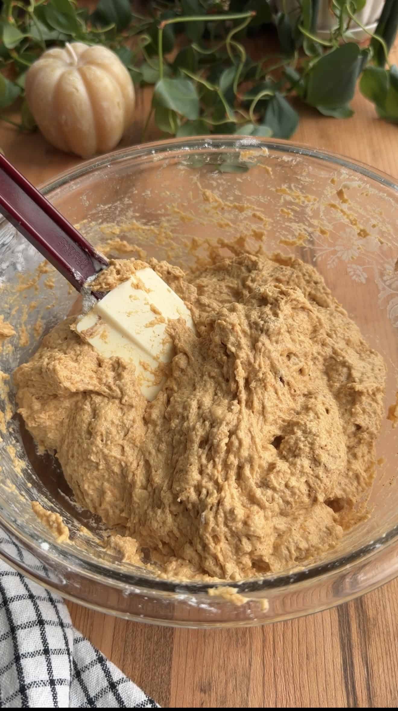 A bowl of sticky orange focaccia dough with a silicone spatula sitting in it.
