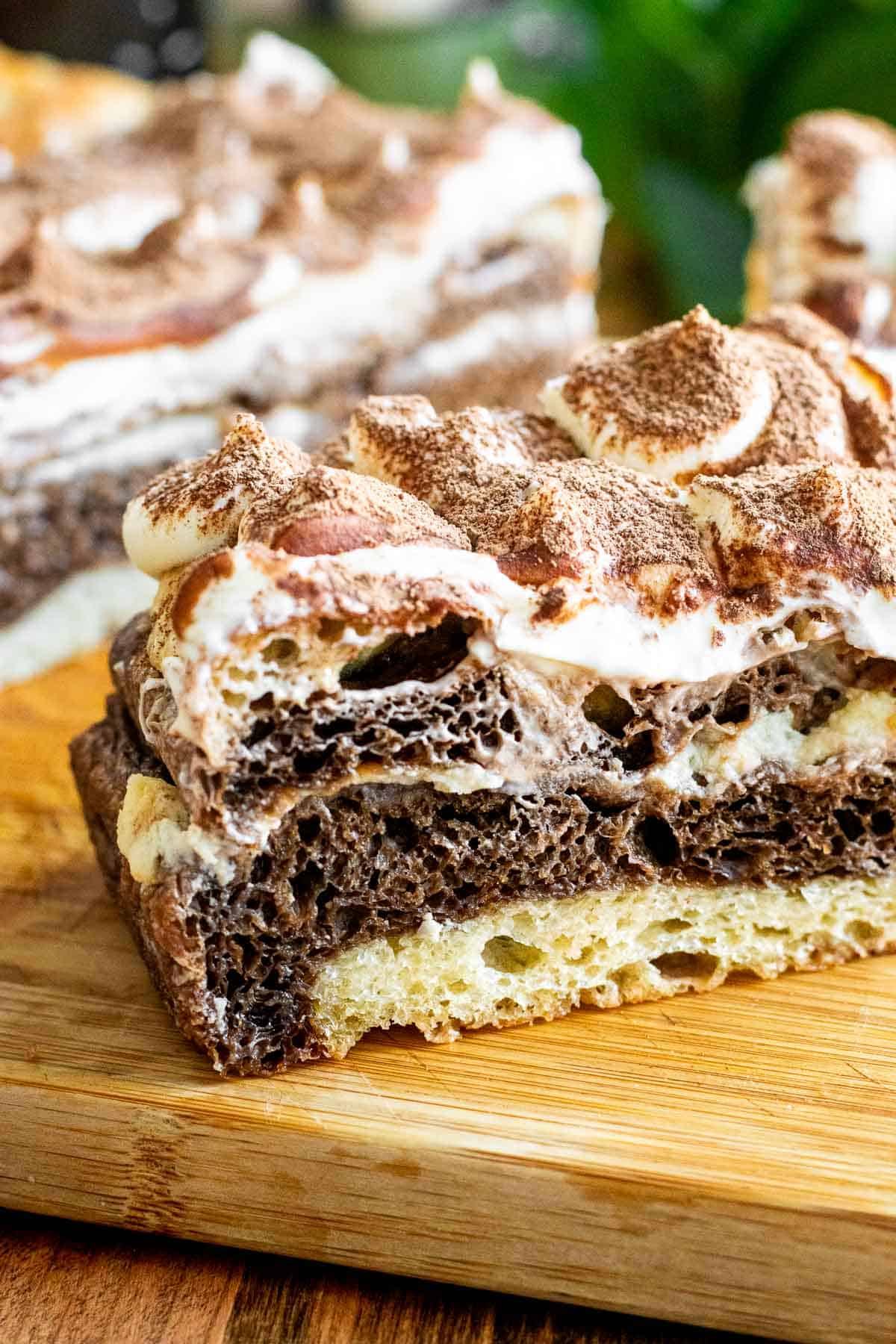 Close-up of marbled focaccia dough with white and black bread layers and a whipped mascarpone topping.