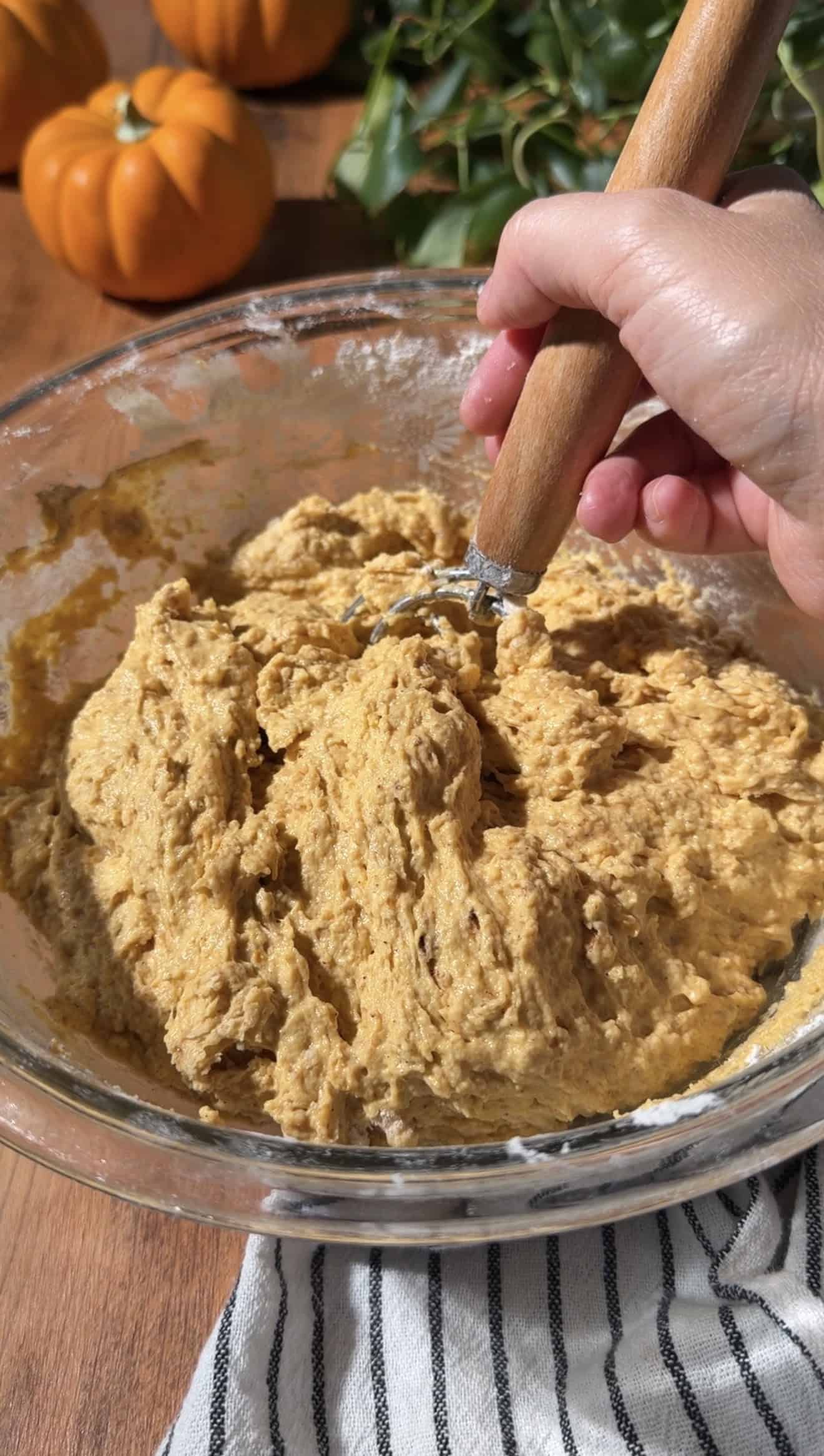 A hand stirring sticky pumpkin bread dough with a Danish dough whisk.