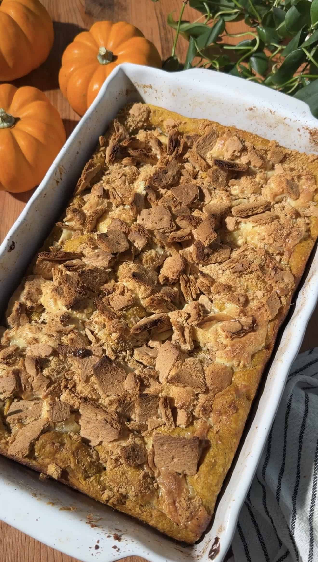 A golden, baked loaf of pumpkin focaccia topped with set cheesecake filling and crushed graham crackers.