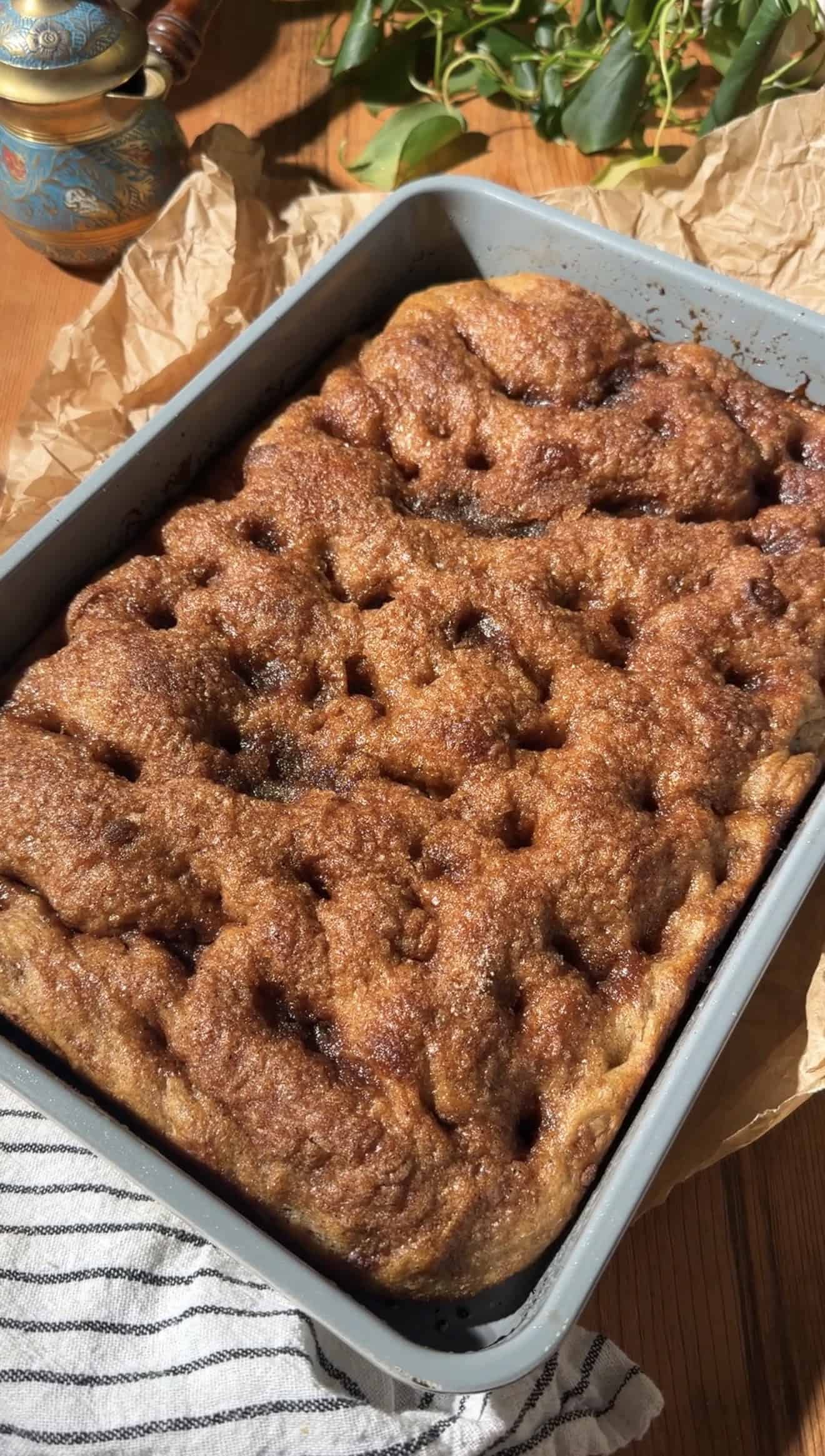 Baked focaccia in a metal baking dish with caramelized, golden sugar on top.
