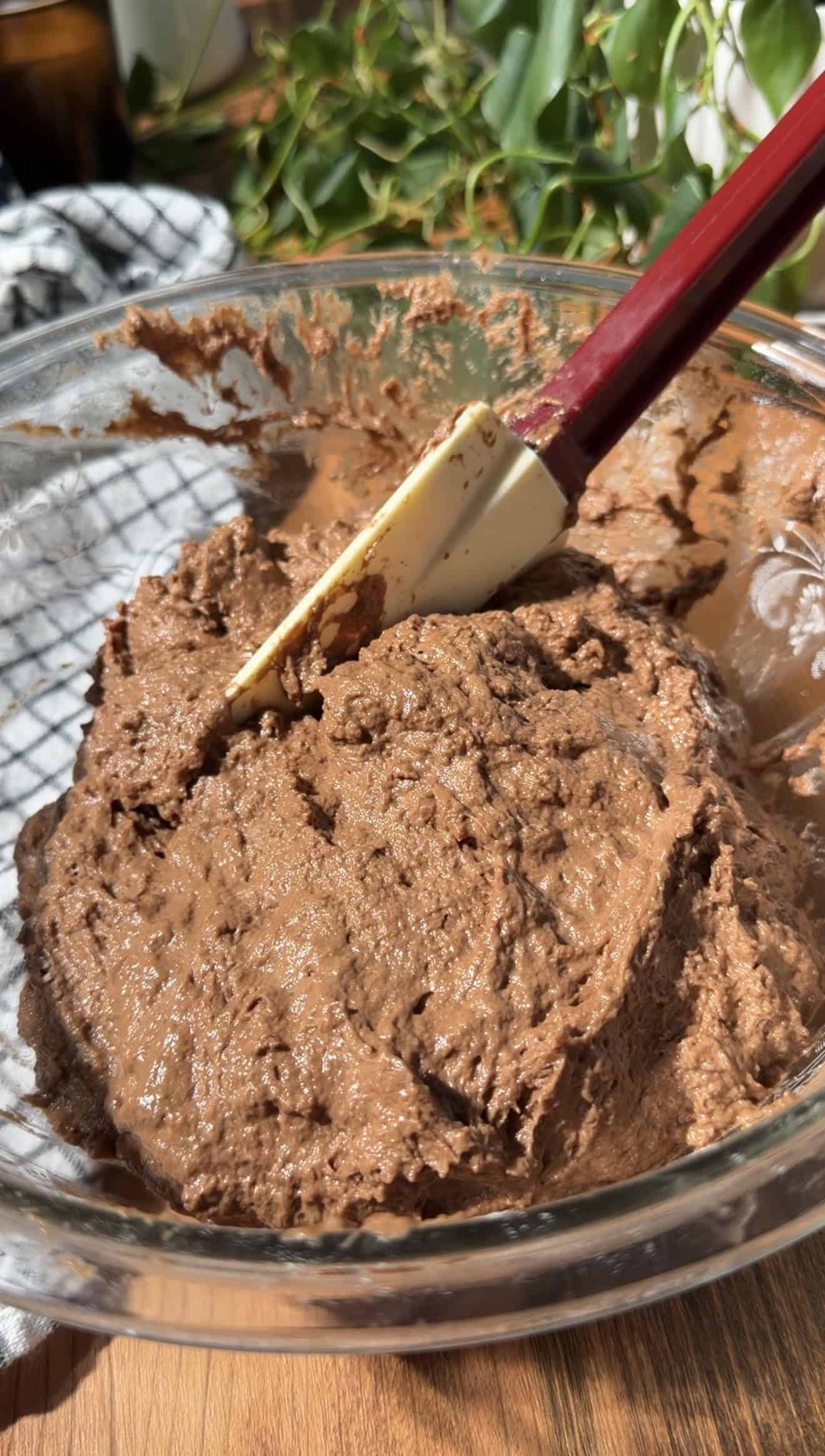 A silicone spatula sitting in a bowl of sticky chocolate bread dough.