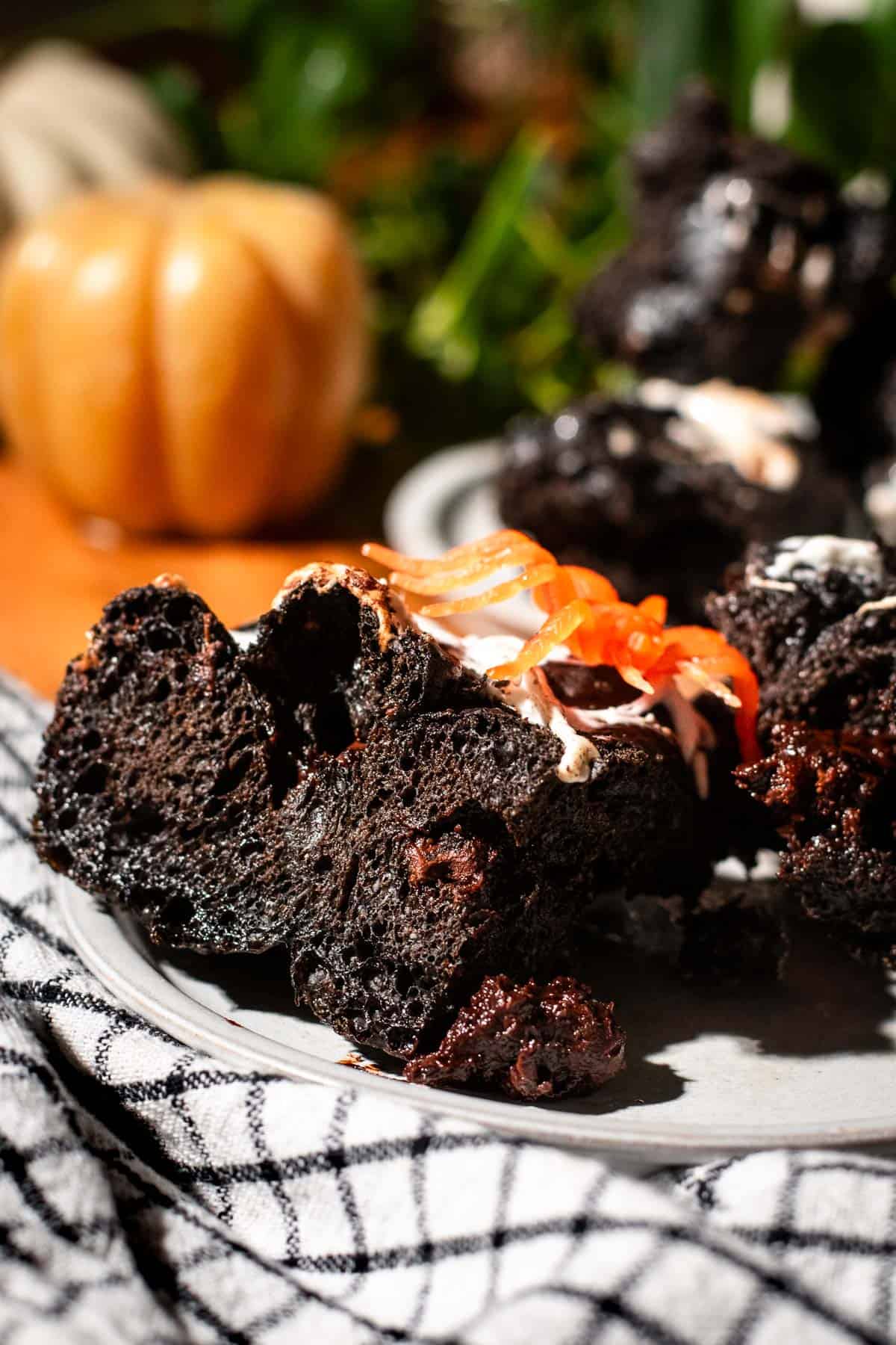 Airy, fluffy focaccia dyed jet black and filled with melted chocolate. Melted marshmallows and a plastic spider sit on top of the slice.