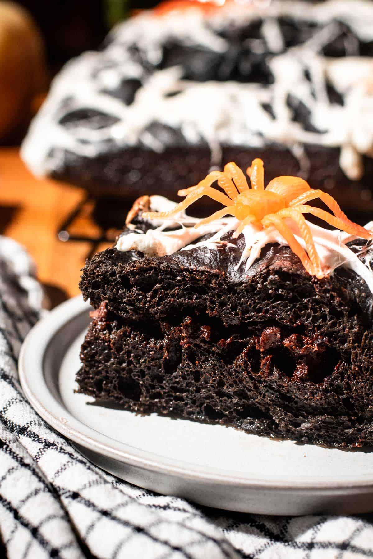 Black focaccia with melted chocolate chips in the filling topped with marshmallow spiderwebs and a plastic orange spider.