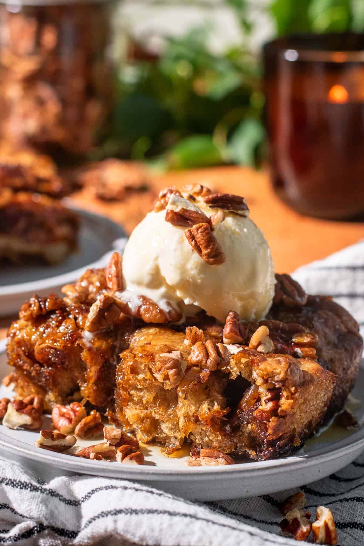 A large square of focaccia topped with candied pecans and a scoop of ice cream. 