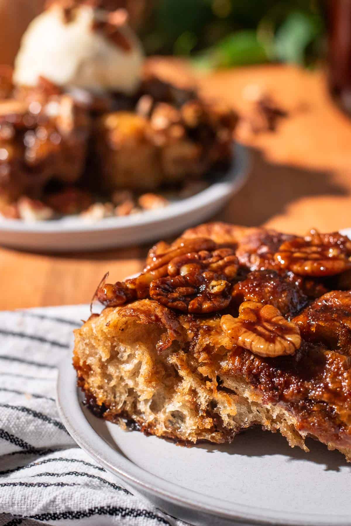 Candied pecans spread on top of a slice of airy golden focaccia on a small grey plate.