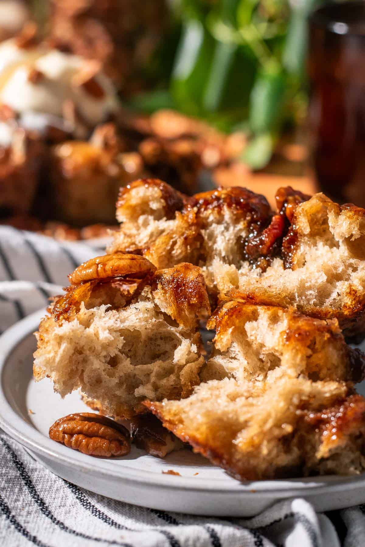 Three torn pieces of airy focaccia bread topped with caramel sauce and whole pecans.