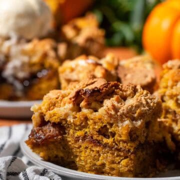 A slice of pumpkin focaccia with a brown sugar layer in the middle and crushed graham crackers on top sitting on a grey plate.