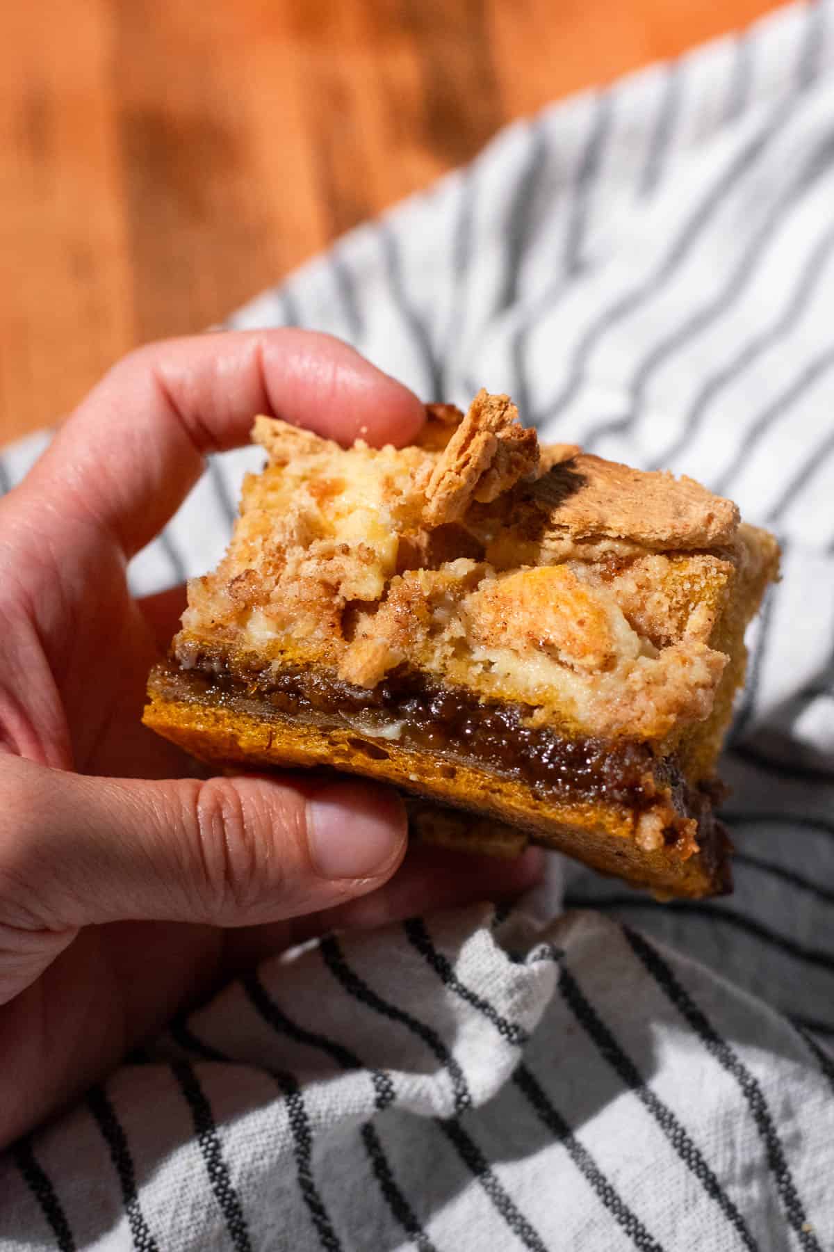 A hand holding A square of focaccia with a fluffy, airy top half and a dense, gummy bottom half.