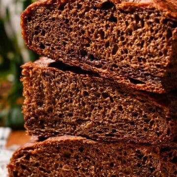 Three thick pieces of chocolate focaccia stacked on a piece of parchment paper.