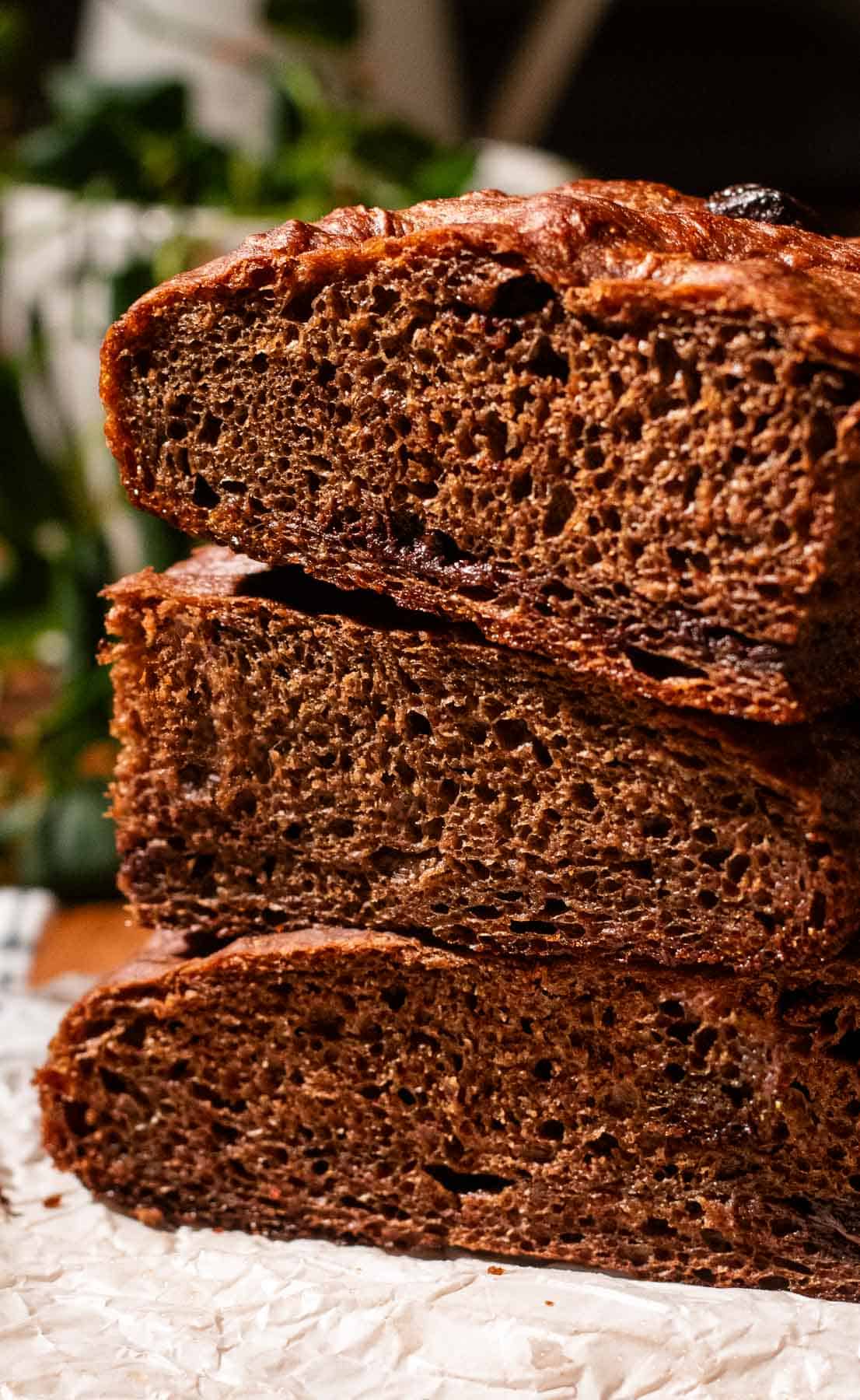Three thick pieces of chocolate focaccia stacked on a piece of parchment paper. 