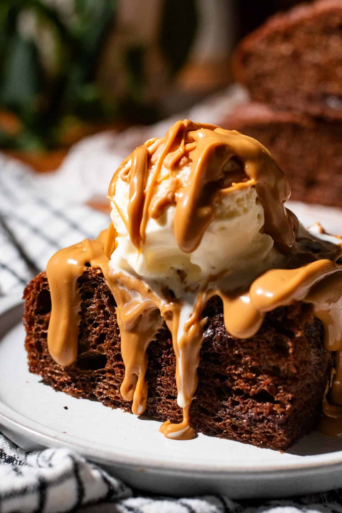 A large piece of triple chocolate focaccia topped with a scoop of ice cream and drizzled nut butter.